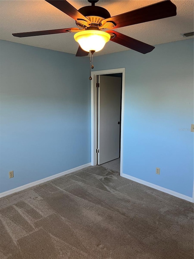 unfurnished room with ceiling fan, a textured ceiling, and carpet