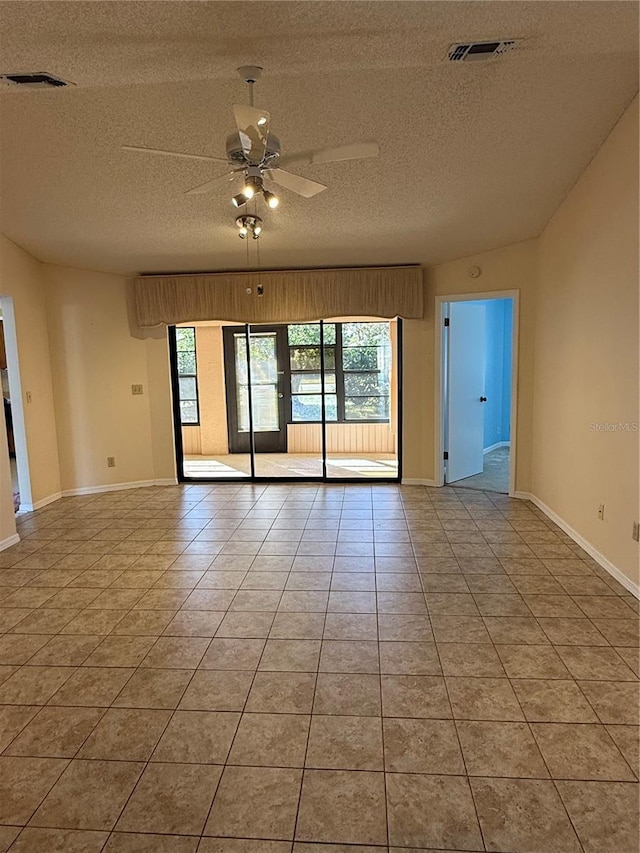 empty room with lofted ceiling, light tile patterned floors, a textured ceiling, and ceiling fan