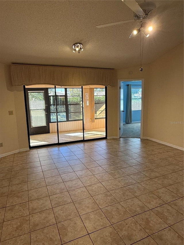 tiled empty room featuring ceiling fan and a textured ceiling