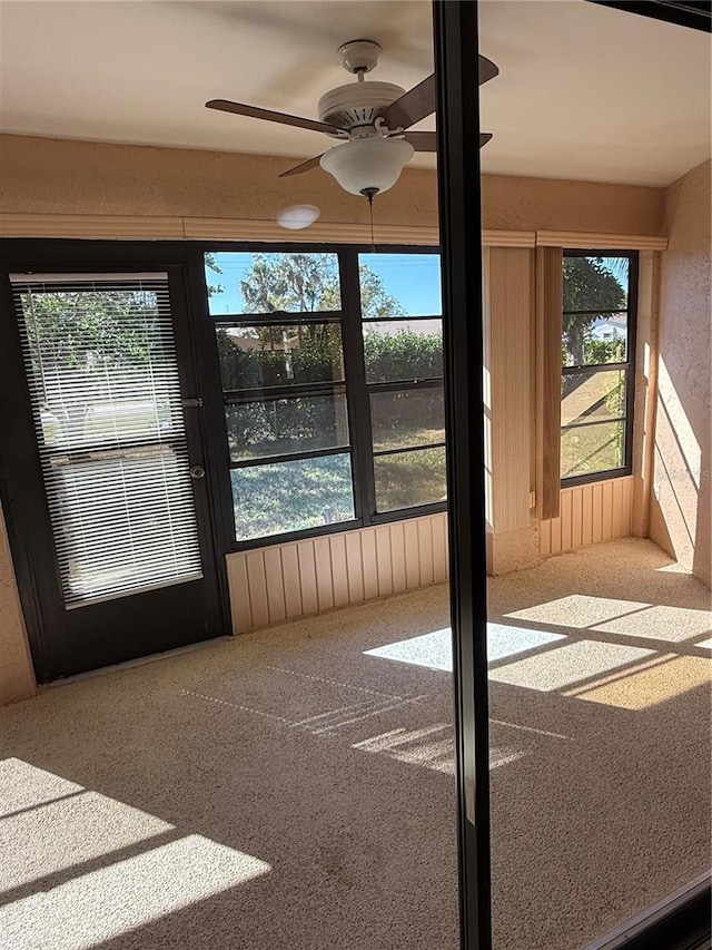 unfurnished sunroom featuring ceiling fan