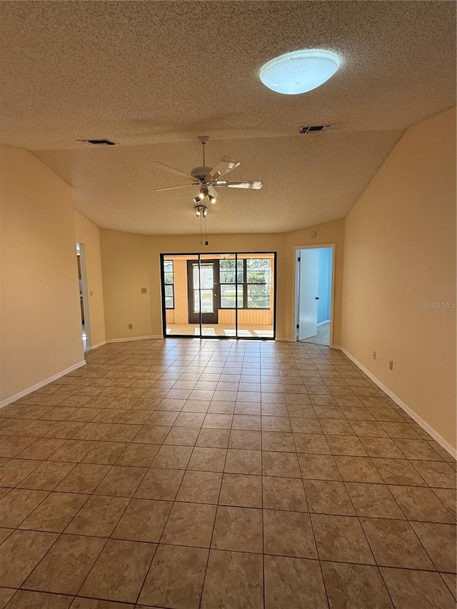 tiled spare room with ceiling fan, visible vents, vaulted ceiling, and a textured ceiling