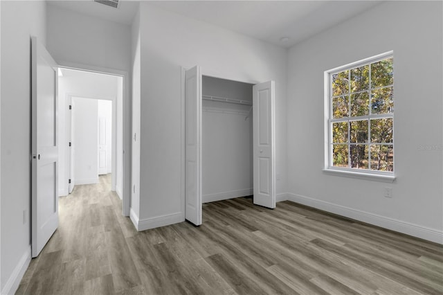 unfurnished bedroom featuring light wood-type flooring, a closet, and multiple windows