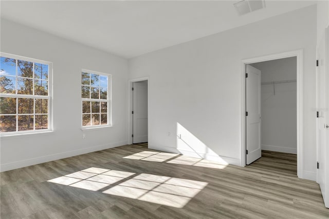 unfurnished bedroom with a spacious closet, light wood-type flooring, and a closet