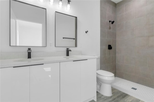 bathroom featuring tiled shower, hardwood / wood-style floors, vanity, and toilet