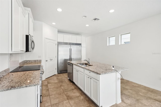 kitchen featuring light stone countertops, appliances with stainless steel finishes, sink, white cabinets, and an island with sink