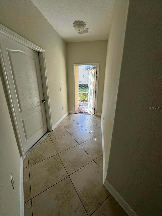 hall featuring light tile patterned floors and a textured ceiling