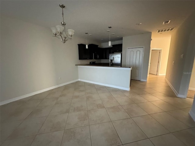 kitchen featuring kitchen peninsula, pendant lighting, a notable chandelier, stainless steel refrigerator, and light tile patterned flooring