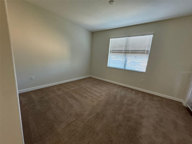 spare room featuring dark carpet