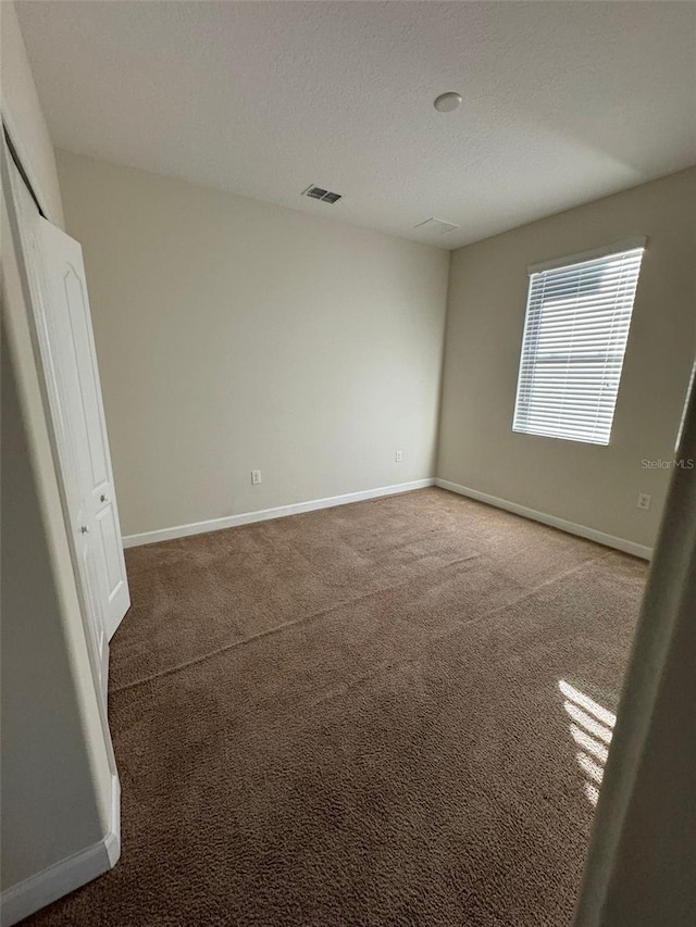 empty room with carpet and a textured ceiling