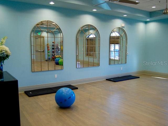 workout area with ceiling fan and wood-type flooring