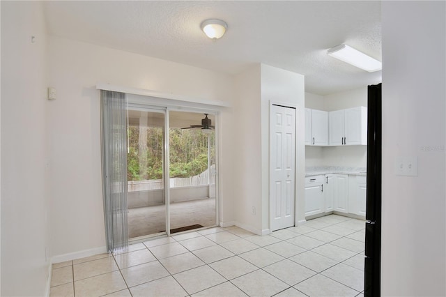 interior space with white cabinets, fridge, ceiling fan, and light tile patterned flooring