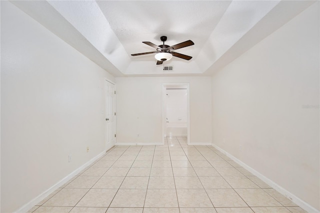 spare room featuring light tile patterned floors, a textured ceiling, a raised ceiling, and ceiling fan