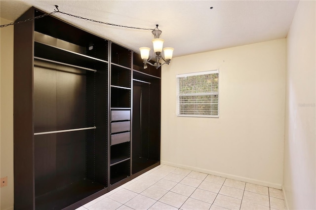 walk in closet with tile patterned floors and a chandelier