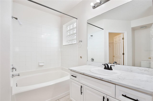 full bathroom featuring a textured ceiling, vanity, toilet, and tiled shower / bath