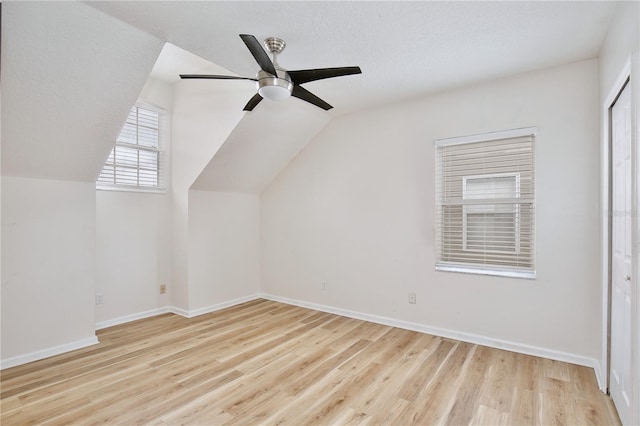 additional living space featuring a textured ceiling, light wood-type flooring, ceiling fan, and lofted ceiling