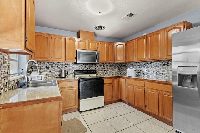 kitchen with decorative backsplash, sink, light tile patterned flooring, and stainless steel appliances