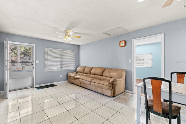 living room featuring ceiling fan, light tile patterned flooring, and a textured ceiling