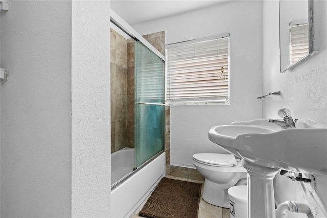 bathroom featuring tile patterned floors, toilet, and bath / shower combo with glass door