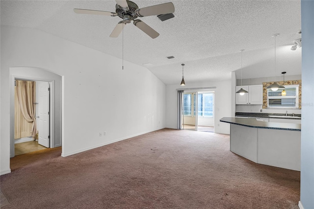 unfurnished living room featuring carpet flooring, ceiling fan, sink, and vaulted ceiling