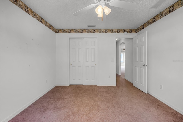 unfurnished bedroom featuring ceiling fan, a textured ceiling, and light carpet