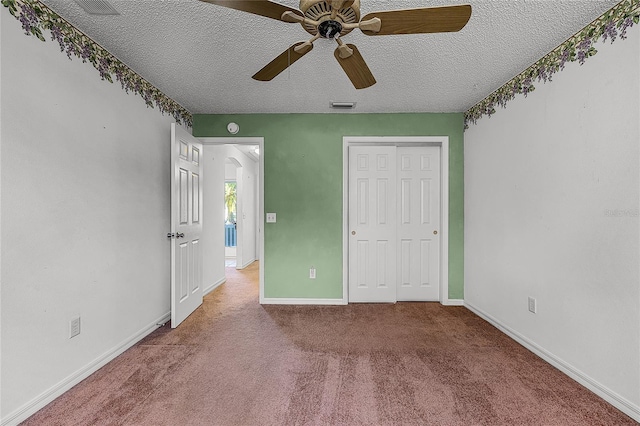 unfurnished bedroom featuring carpet, ceiling fan, a textured ceiling, and a closet