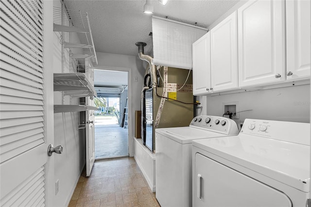 laundry room with washer and clothes dryer, cabinets, and a textured ceiling