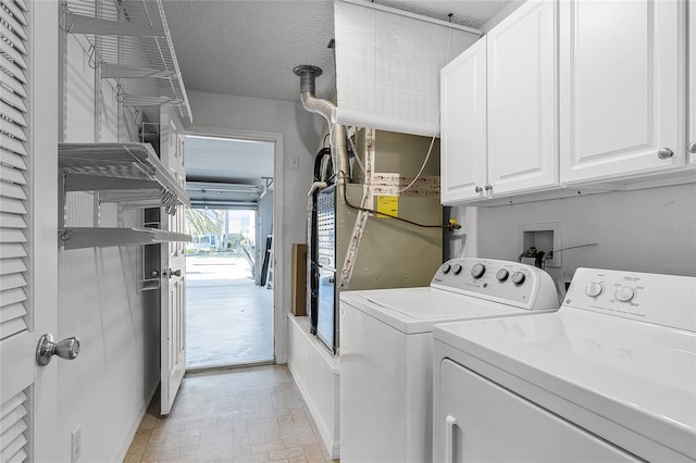 clothes washing area with washer and clothes dryer, cabinets, and a textured ceiling