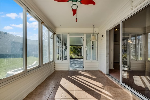 unfurnished sunroom featuring a mountain view, ceiling fan, and a healthy amount of sunlight