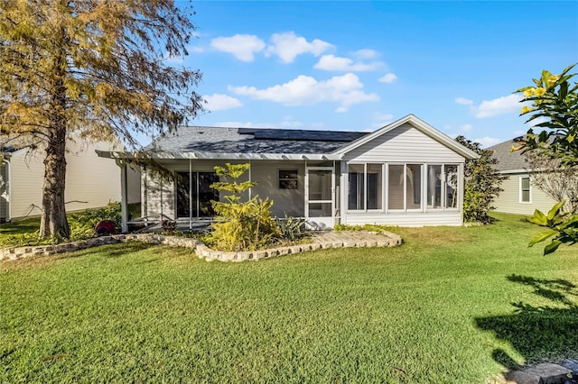 rear view of house featuring solar panels, a lawn, and a sunroom