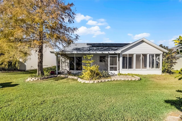 back of property with a sunroom and a yard