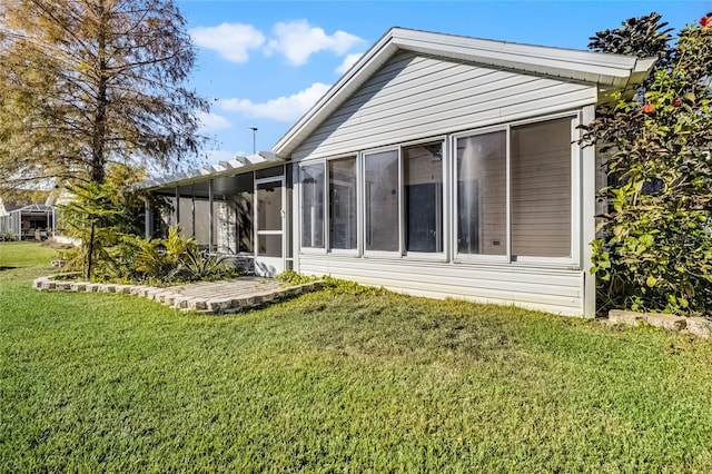 back of house featuring a sunroom and a lawn