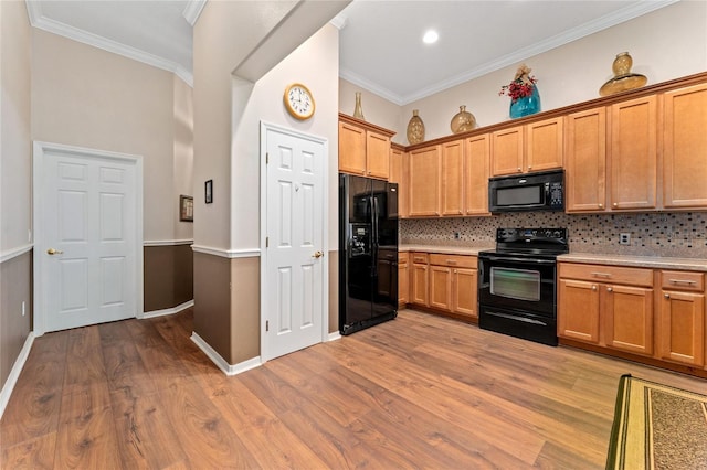 kitchen featuring light wood-type flooring, backsplash, ornamental molding, and black appliances