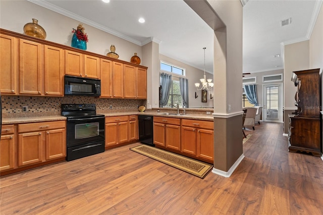 kitchen with sink, a healthy amount of sunlight, hardwood / wood-style floors, decorative light fixtures, and black appliances