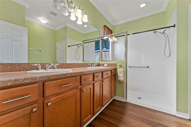 bathroom featuring hardwood / wood-style flooring, vanity, a tile shower, and crown molding