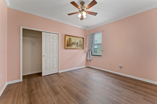 unfurnished bedroom featuring hardwood / wood-style flooring, ceiling fan, ornamental molding, and a closet