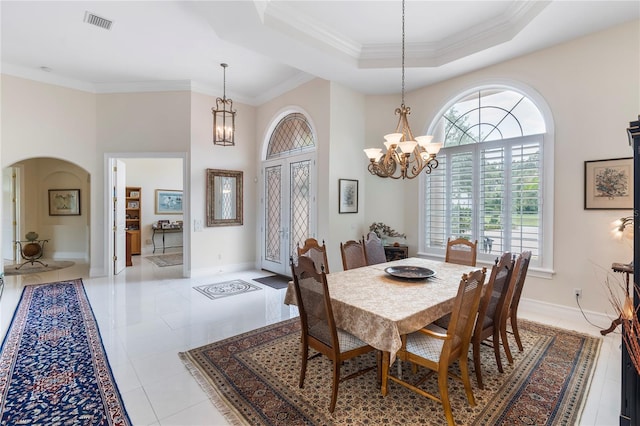 dining room with a tray ceiling, light tile patterned flooring, ornamental molding, and an inviting chandelier