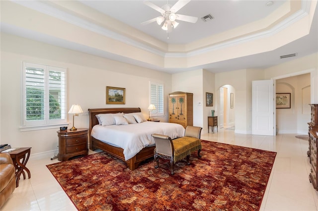 bedroom featuring a tray ceiling, ceiling fan, light tile patterned floors, and ornamental molding