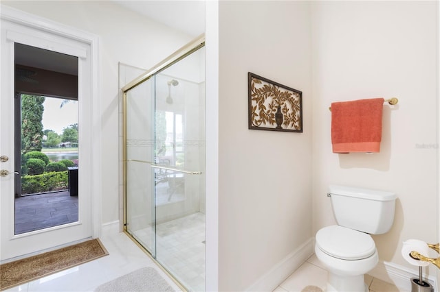 bathroom featuring tile patterned flooring, toilet, and a shower with shower door