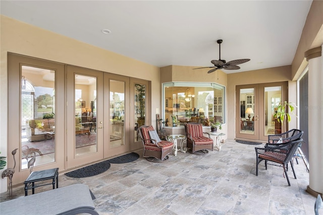 sunroom / solarium featuring french doors and ceiling fan with notable chandelier