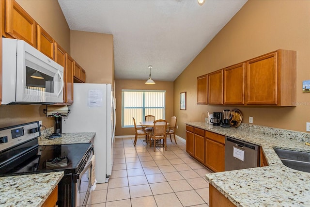 kitchen featuring sink, light stone counters, lofted ceiling, light tile patterned floors, and appliances with stainless steel finishes