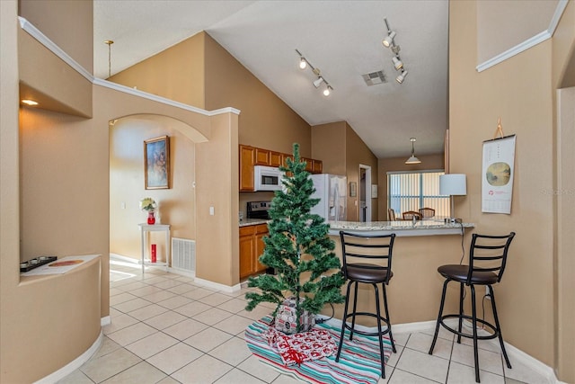 kitchen featuring a breakfast bar area, kitchen peninsula, light tile patterned flooring, and white appliances