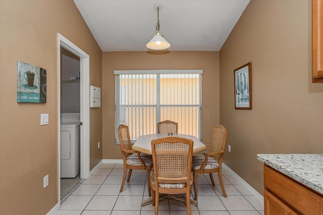 dining room with light tile patterned floors, vaulted ceiling, and washer / dryer