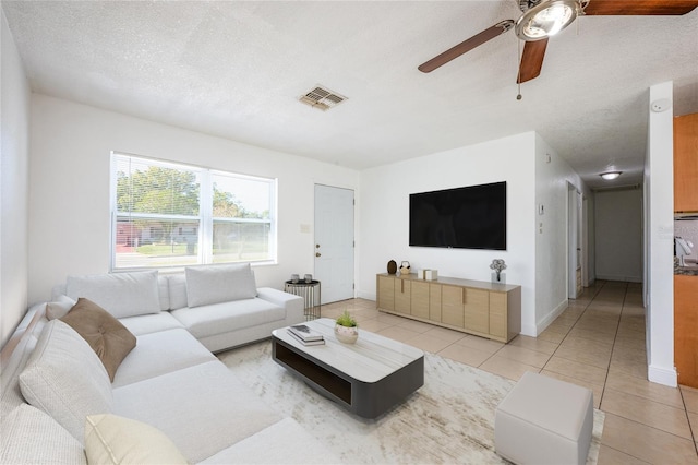 living room with ceiling fan, light tile patterned flooring, and a textured ceiling