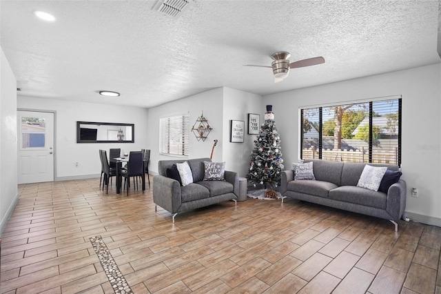 living room with a textured ceiling, light hardwood / wood-style floors, and ceiling fan