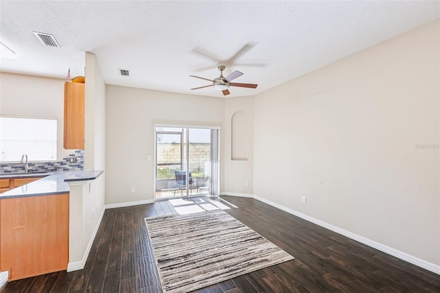 unfurnished living room with a textured ceiling, dark hardwood / wood-style floors, ceiling fan, and sink