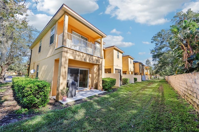 rear view of property with a lawn and a balcony