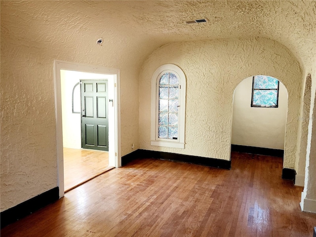 unfurnished room with dark hardwood / wood-style flooring, a textured ceiling, and lofted ceiling