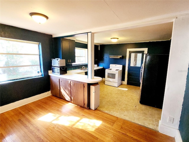 kitchen with kitchen peninsula, plenty of natural light, white appliances, and light wood-type flooring