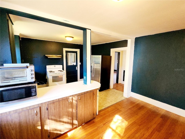 kitchen featuring kitchen peninsula, appliances with stainless steel finishes, and light hardwood / wood-style flooring