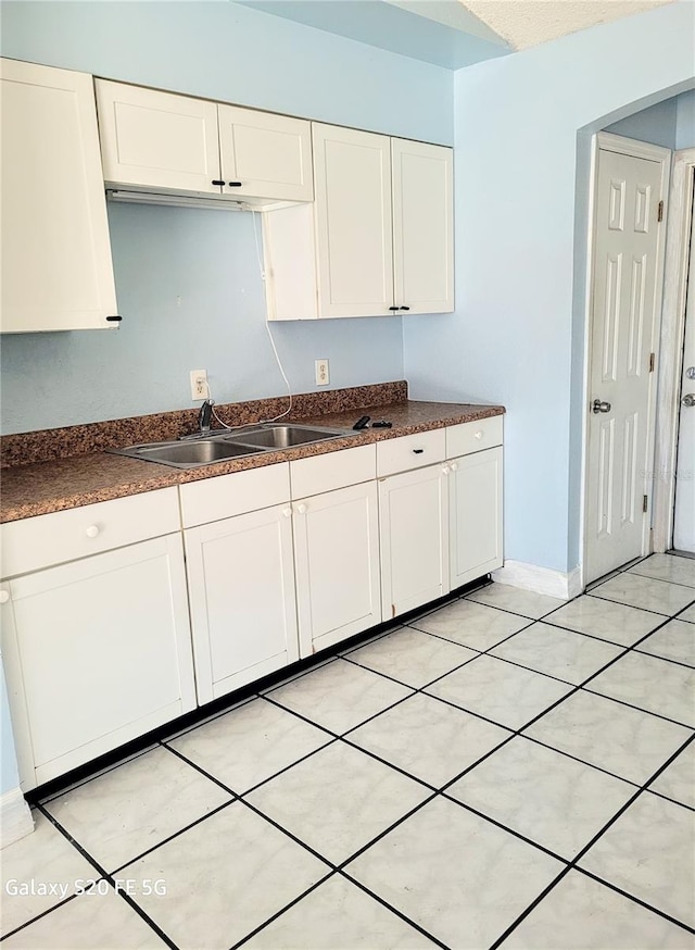 kitchen featuring white cabinets, light tile patterned floors, and sink